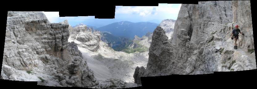 Martin holds on to the via ferrata cable above a rough, rocky ravine